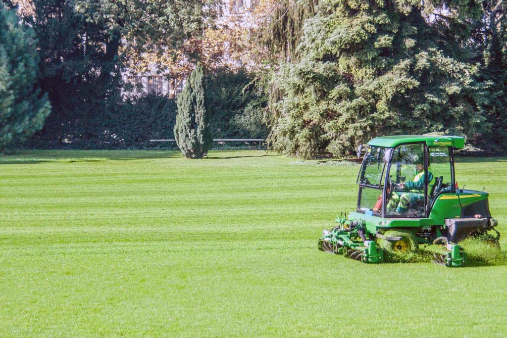 Mann auf einem Aufsitzrasenmäher mäht Rasen