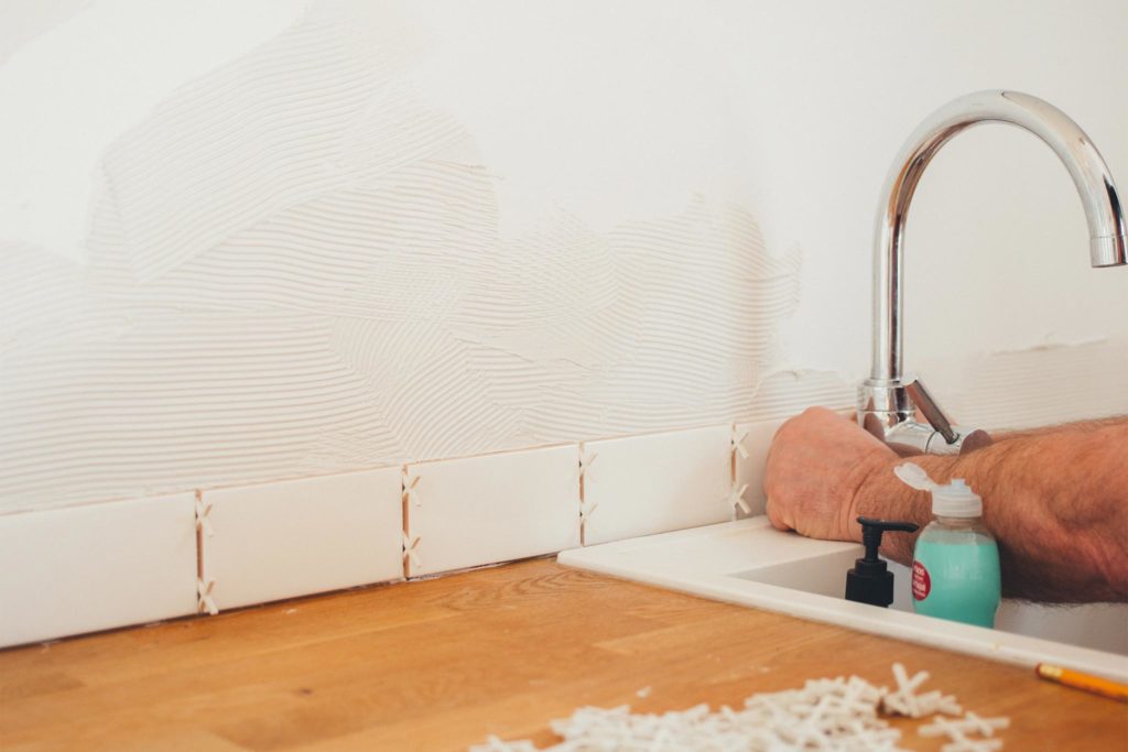 Mann befestigt Kacheln an einer Küchenwand